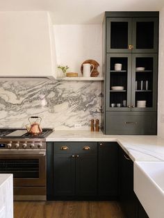 a kitchen with marble counter tops and black cabinets, along with an oven top stove