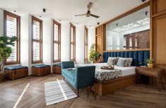 a bed room with a neatly made bed and wooden floors next to two large windows