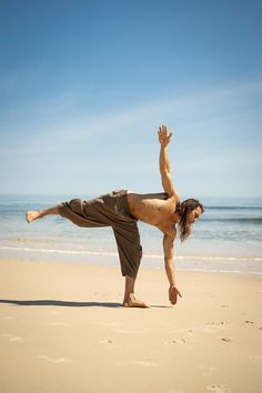 a man doing yoga on the beach with his feet in the air and one leg up