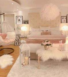 a bedroom decorated in white and pink with candles on the floor, chandelier above bed