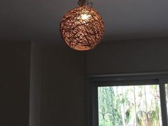 a light fixture hanging from the ceiling in a room next to a window with an open door