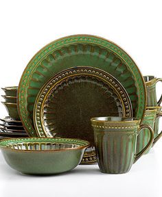 green dishes and cups are stacked on top of each other with gold trimmings