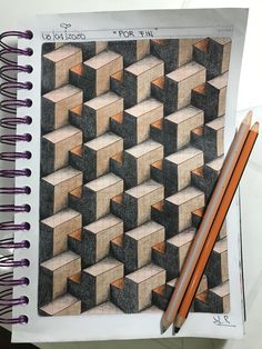 pencils are sitting on top of a drawing book with an image of cubes