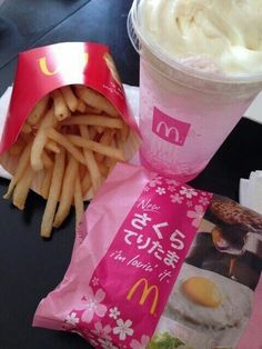 a cup of ice cream next to some french fries on a table with a packet of macaroni and cheese