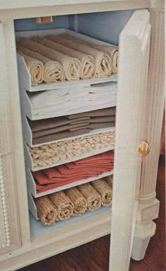 an open cabinet filled with rolled up blankets