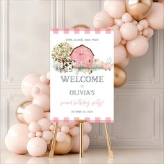 a welcome sign surrounded by balloons in front of a white wall with pink and gold accents