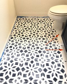 a white toilet sitting in a bathroom next to a black and white tiled floor with an arrow pointing towards it