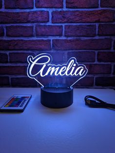 an illuminated lamp with the word omelia on it next to a remote control