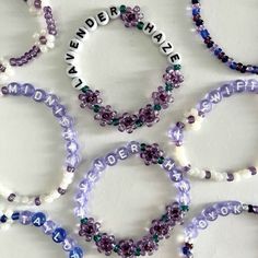 several bracelets with words written on them and beaded in white, purple, green and blue beads