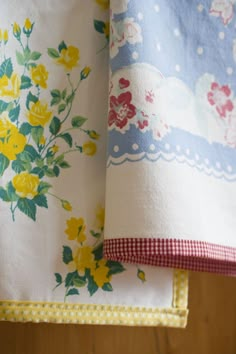 two floral bedspreads with yellow and red flowers on them, hanging from a bed rail