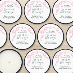 baby shower favors with pink and black trims on wooden table next to lit candle