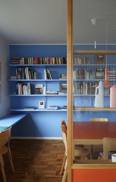 a room with blue walls and shelves filled with books on the far wall is a dining table