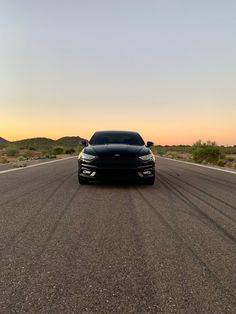 a black car is parked on the side of the road in front of an orange sky