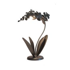 a metal sculpture with flowers and leaves on it's base, against a white background