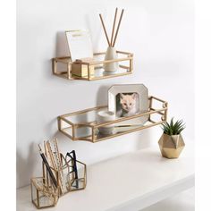 two gold shelves with pictures and candles on them next to a plant in a vase