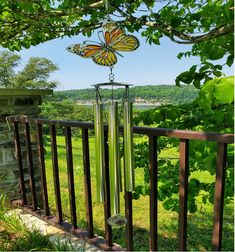 a wind chime in the shape of a butterfly on a fence with green grass