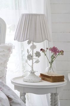 a white table with flowers and a lamp on it