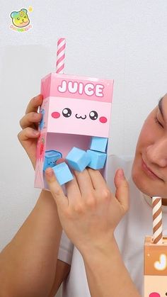 a woman holding up a pink box with blue cubes in it's mouth