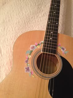 an acoustic guitar with flowers painted on it