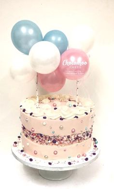 a pink cake with white frosting and balloons