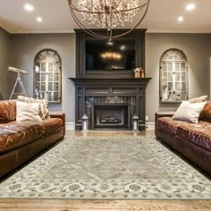 a living room with two couches and a rug in front of a fire place