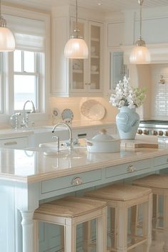 a kitchen island with stools in front of it and lights hanging from the ceiling