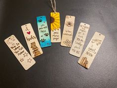 five wooden bookmarks with writing on them and a sunflower hanging from the top