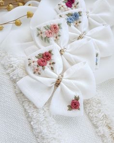 two white bows with pink, blue and red flowers are on top of a white blanket