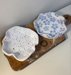 two white and blue dishes sitting on top of a wooden tray next to each other