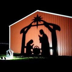 a nativity scene is shown in front of a barn at night with the shadow of two people and a baby jesus