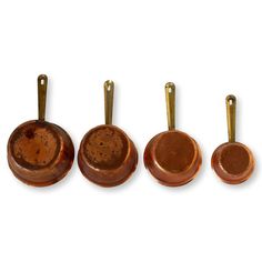 four copper colored pans are lined up in a row on a white background,