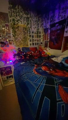 a spiderman themed bed in a bedroom with purple lighting and posters on the wall