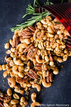 roasted nuts with rosemary sprigs and seasoning next to a red strainer