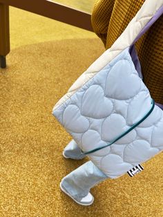 a close up of a person's feet holding a purse on the ground in front of a bench