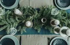 the table is set with dishes, silverware and greenery for an elegant dinner