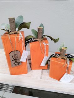 three pumpkins with tags tied to them sitting on a table next to each other