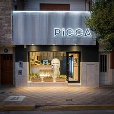 a store front with the word picca lit up on it's side at night