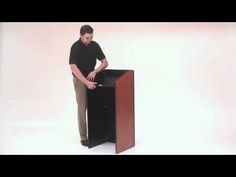 a man standing at a podium with his hand on the back of it's cabinet