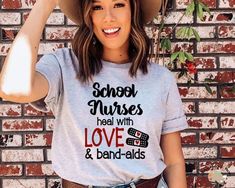 a woman wearing a t - shirt that says school nurses heal with love and band aids