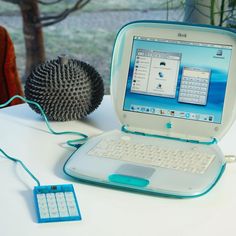 an open laptop computer sitting on top of a white table next to a blow dryer