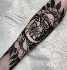 a black and white tattoo design with flowers on the arm, done by an artist