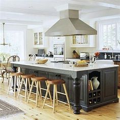 a large kitchen island with stools next to it and an oven in the middle