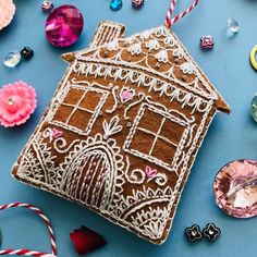 a gingerbread house ornament surrounded by other christmas ornaments and decorations on a blue surface