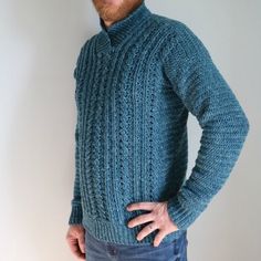 a man with his hands on his hips wearing a blue knitted turtle neck sweater