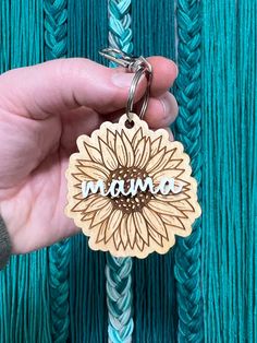 a person holding a keychain with the word mama on it and a sunflower