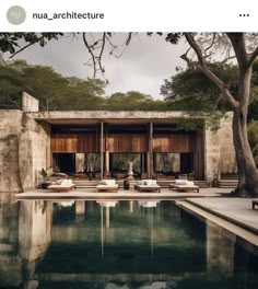 an outdoor swimming pool with chaise lounges next to it and trees in the background