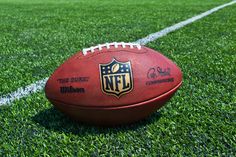 a football sitting on top of a field with the nfl written on it's side