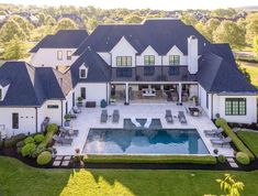 an aerial view of a large house with a pool in the front yard and landscaping around it