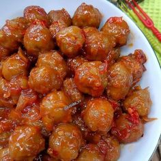 a white plate topped with meatballs covered in sauce on top of a wooden table