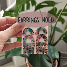 a pair of earrings is shown in front of a plant with the words earring mold